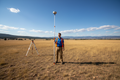 Surveyor holding extended 3m telescopic rod in a field